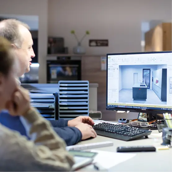 Küchenplaner präsentiert am Computer eine 3D-Visualisierung einer modernen Einbauküche. Professionelle Küchenplanung mit Software für individuelle Traumküchen.